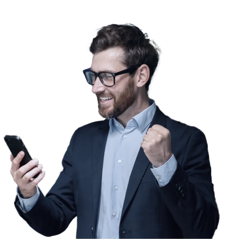 A man in a business suit wearing glasses is looking at his smartphone with a smile of excitement and triumph, raising his fist in a celebratory gesture.