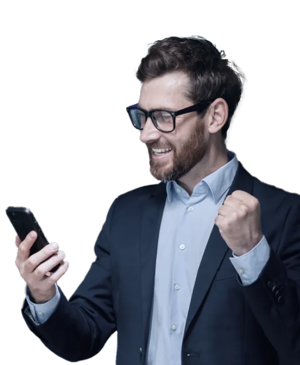 A man in a business suit wearing glasses is looking at his smartphone with a smile of excitement and triumph, raising his fist in a celebratory gesture.